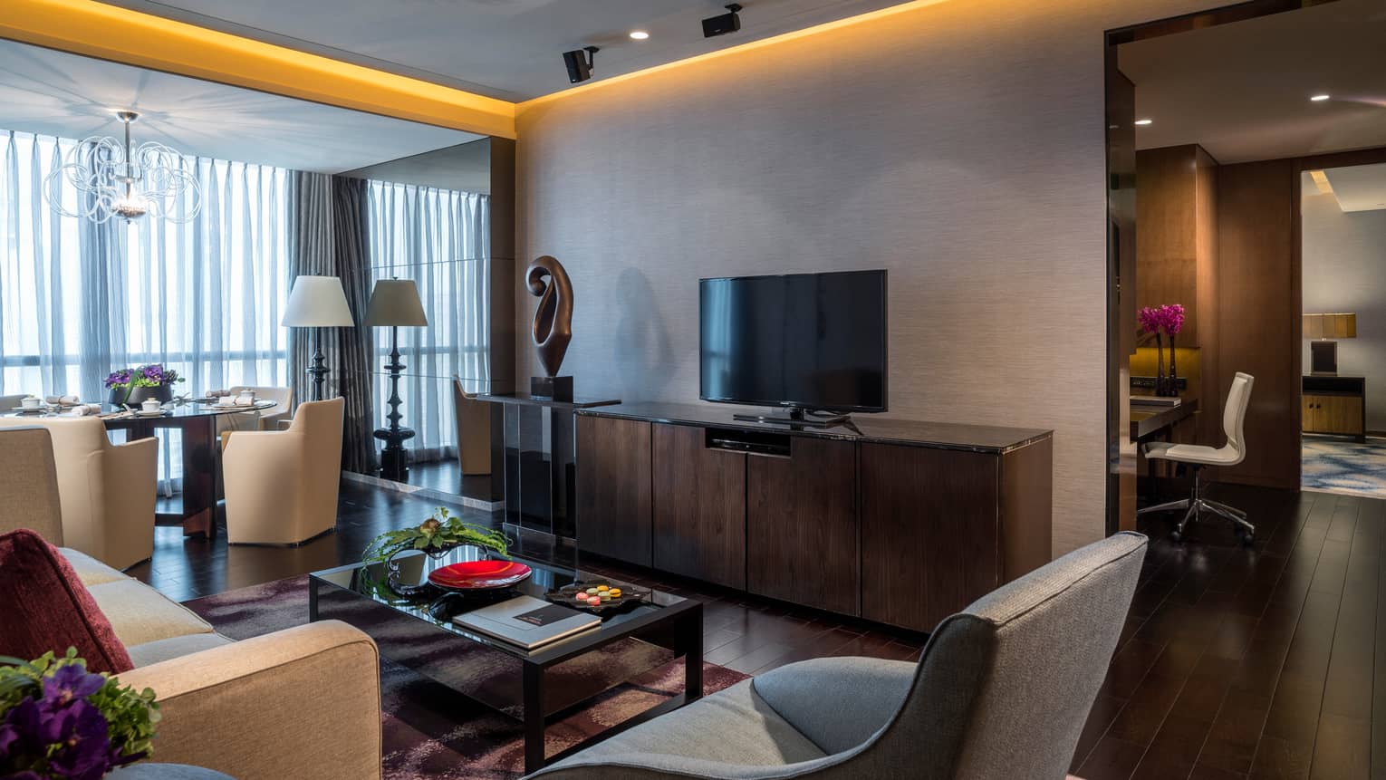 Ambassador Suite modern seating area, dresser and TV, sculpture, dining table near window