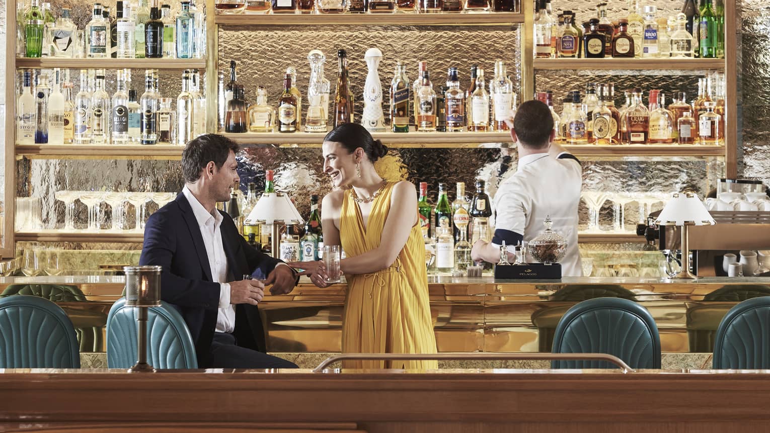 A man and woman at a bar with a bartender making a drink.