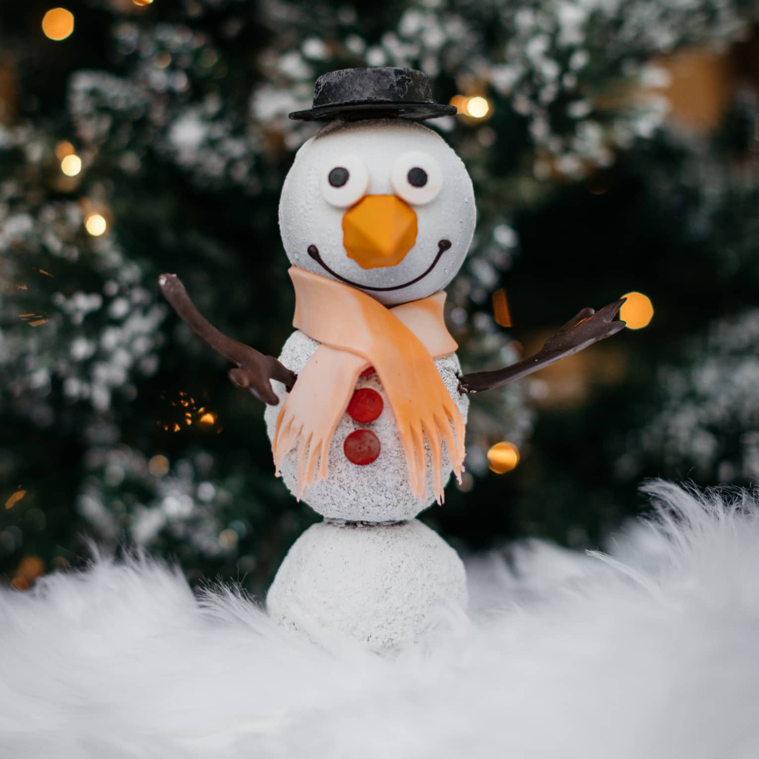 A toy snowman in front of a Christmas tree.