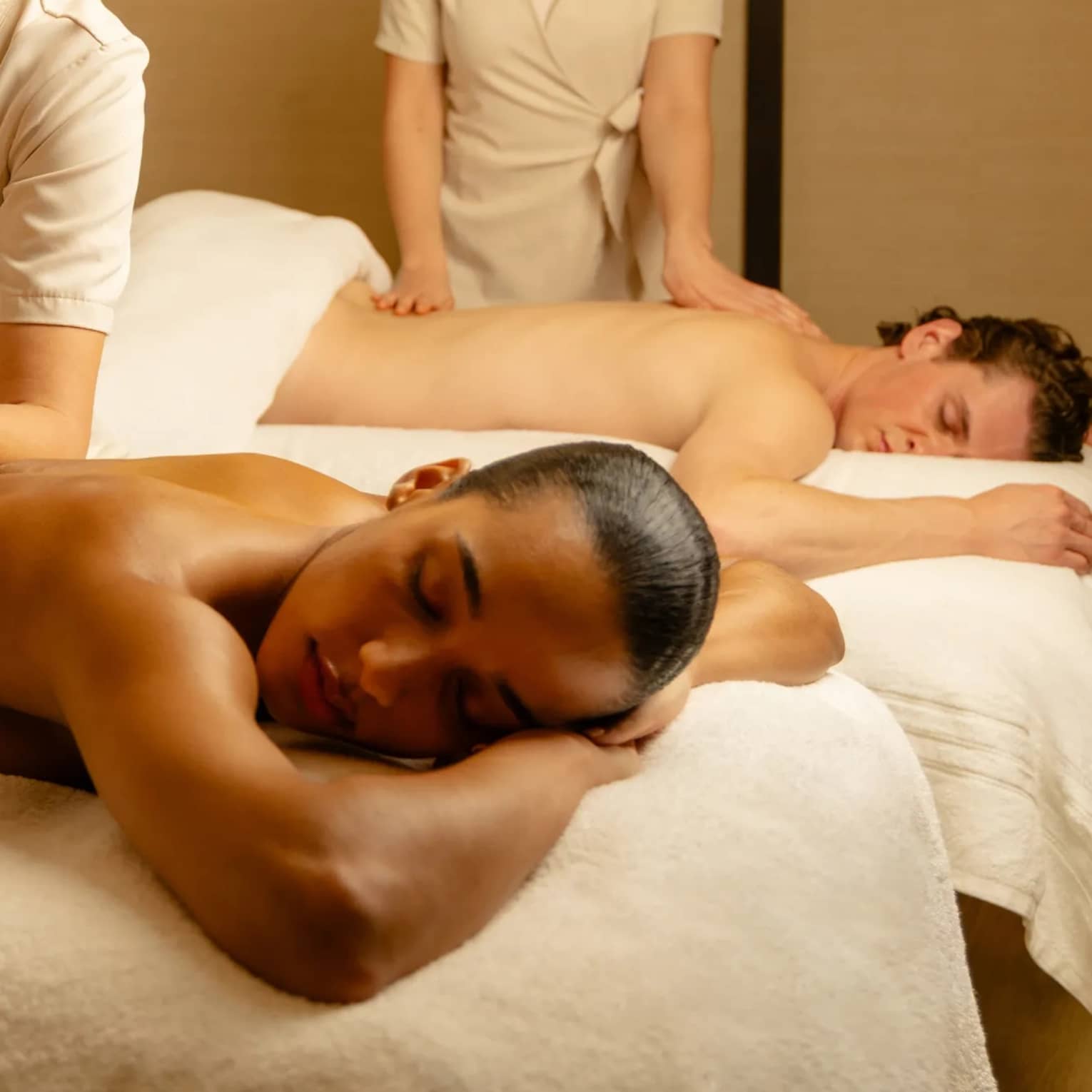 Couples massage in a warmly lit spa room