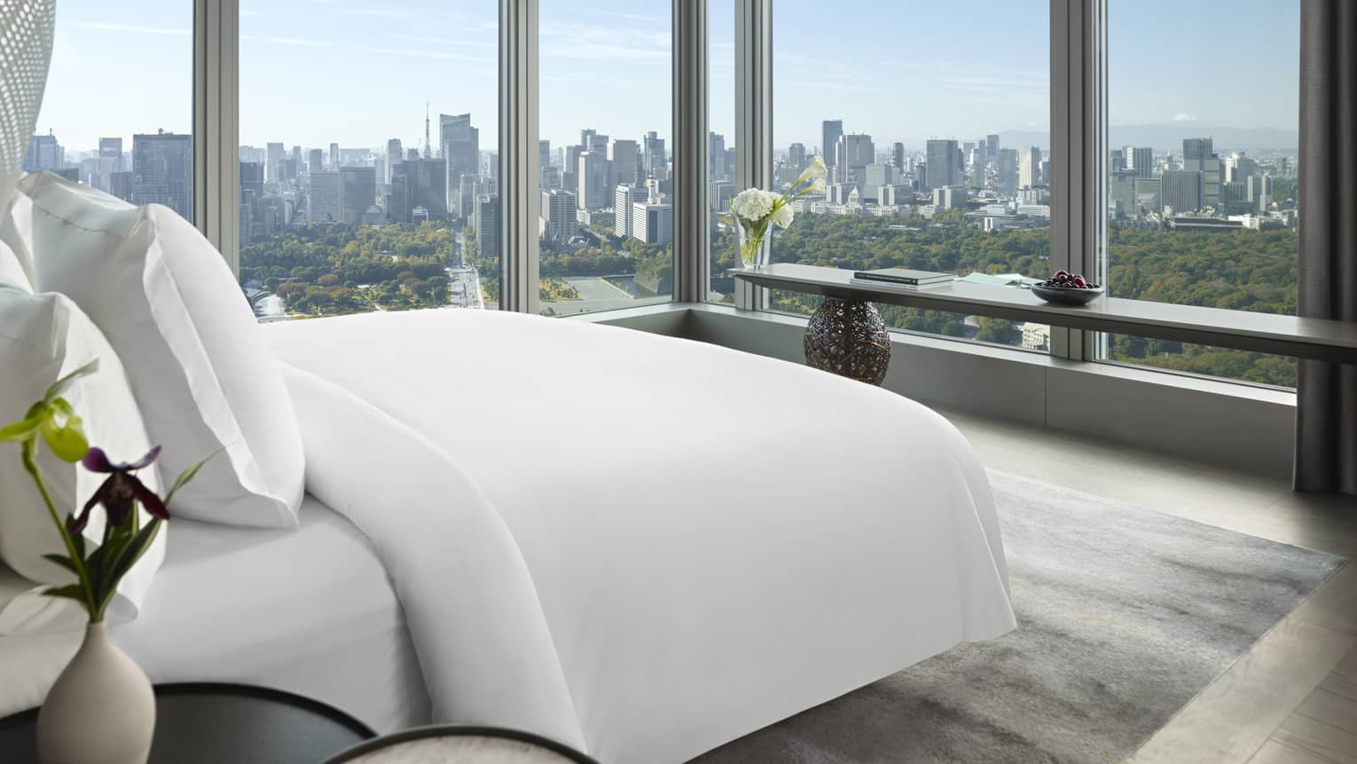 Tokyo suites bedroom with floor-to-ceiling windows offering panoramic city skyline view