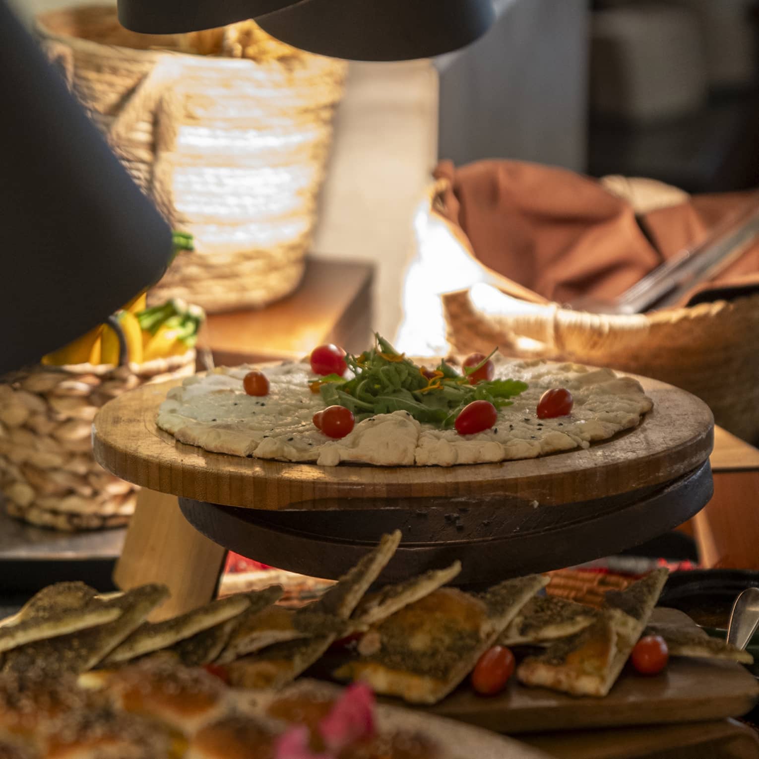 Cheese and za'atar manakeesh garnished with grape tomatoes and garnish on round cutting board