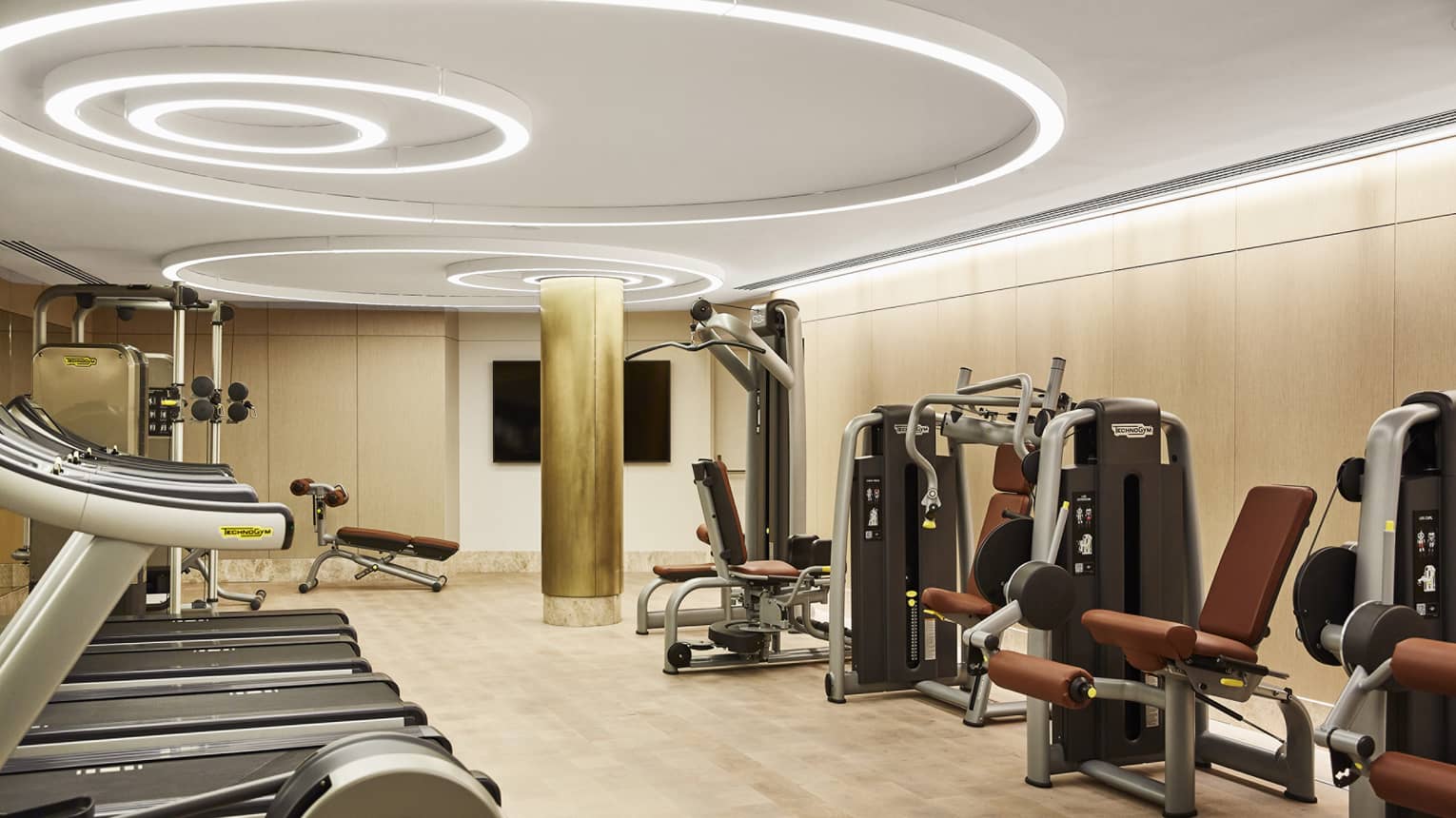 Fitness centre with three treadmills, weight-training machines, modern circular lights on the ceiling