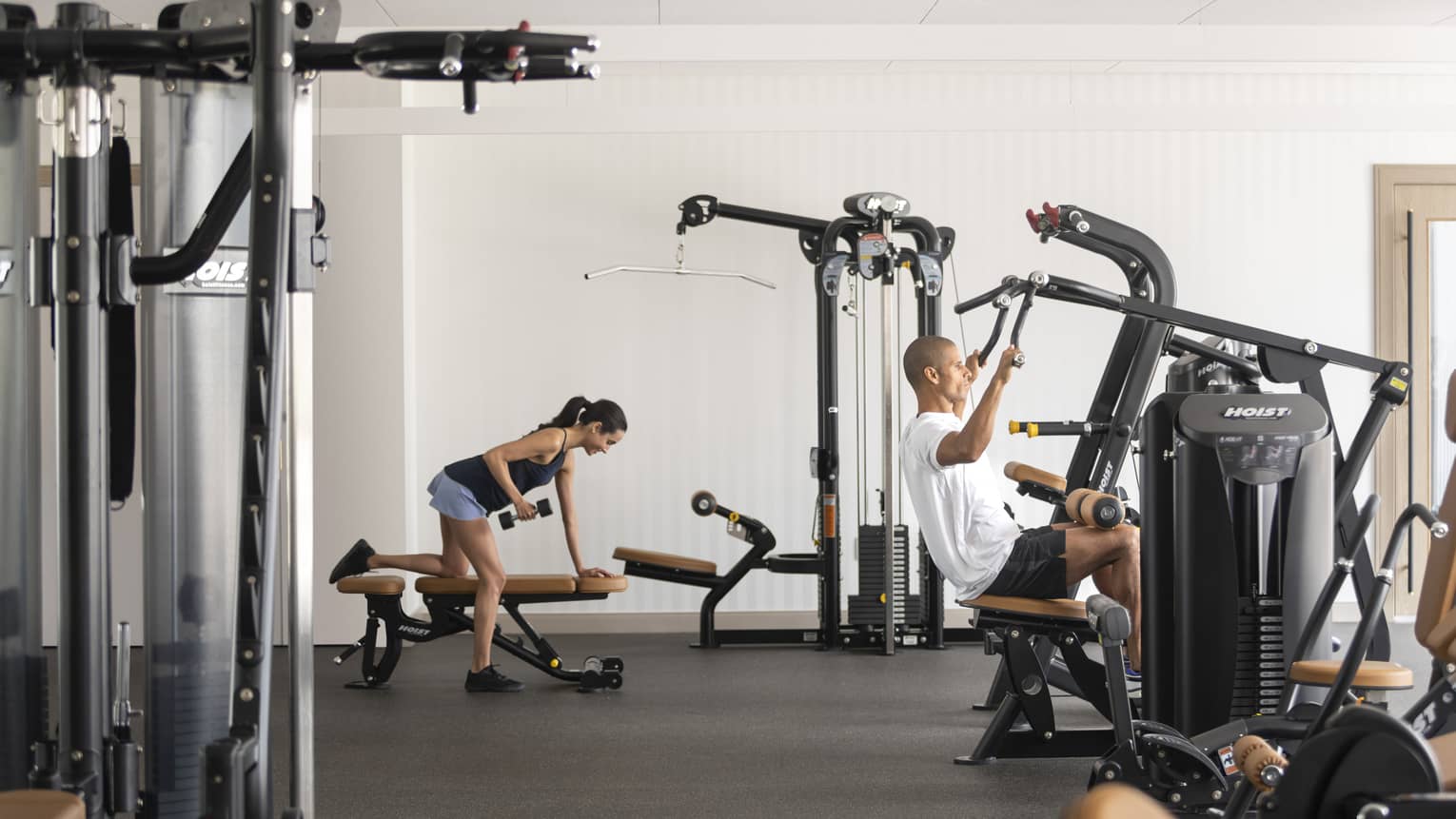 A man and woman exercising in a well equipped hotel gym.
