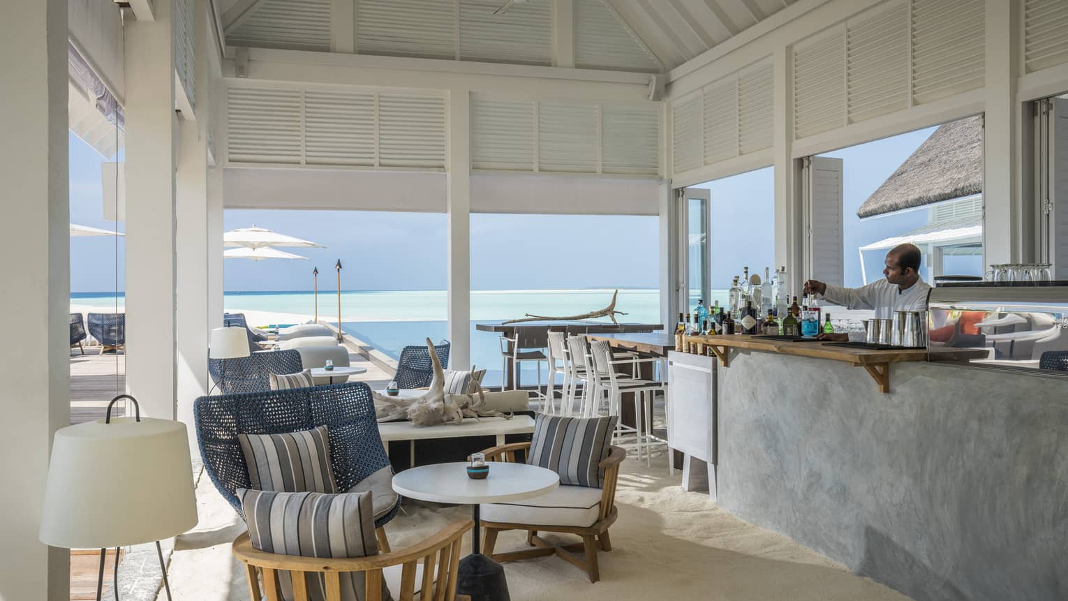 A comfortable, oceanside bar at the Blu Beach Club with plush chairs and a variety of cocktail selections