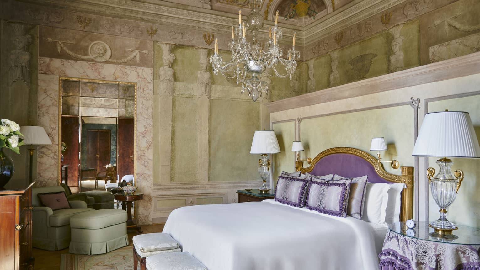 Frescoed Executive Suite bedroom with king bed, purple headboard and throw pillows, glass lamps and chandelier, at Four Seasons Hotel Florence