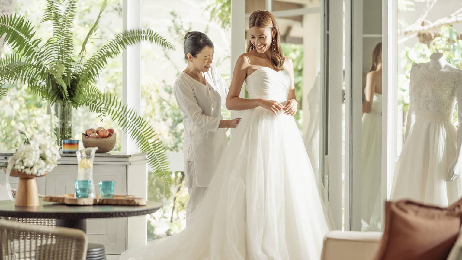 Wedding tailor helps bride in her wedding dress