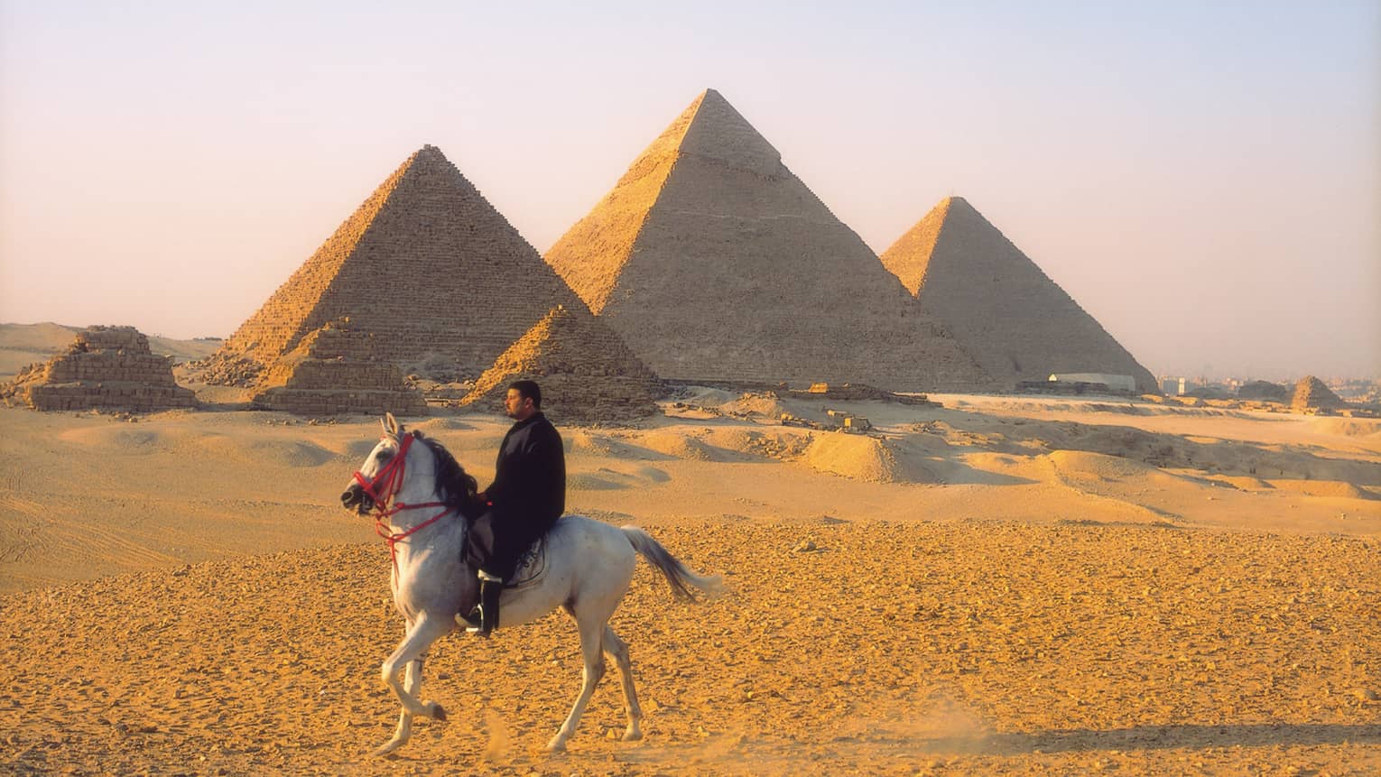 Horseman riding by pyramids