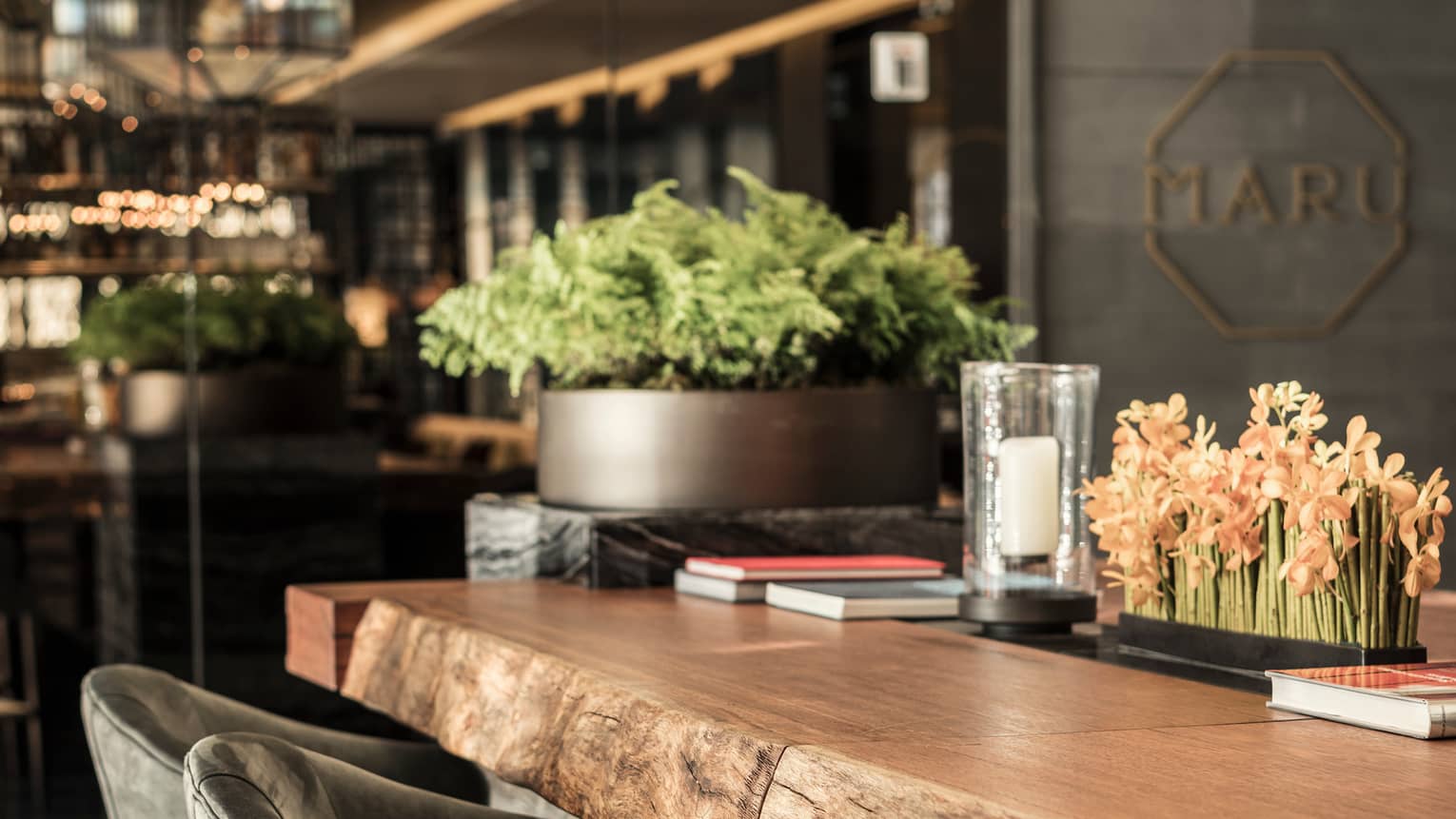 Close-up of rustic wood bar with flowers, candles, books in Maru lounge