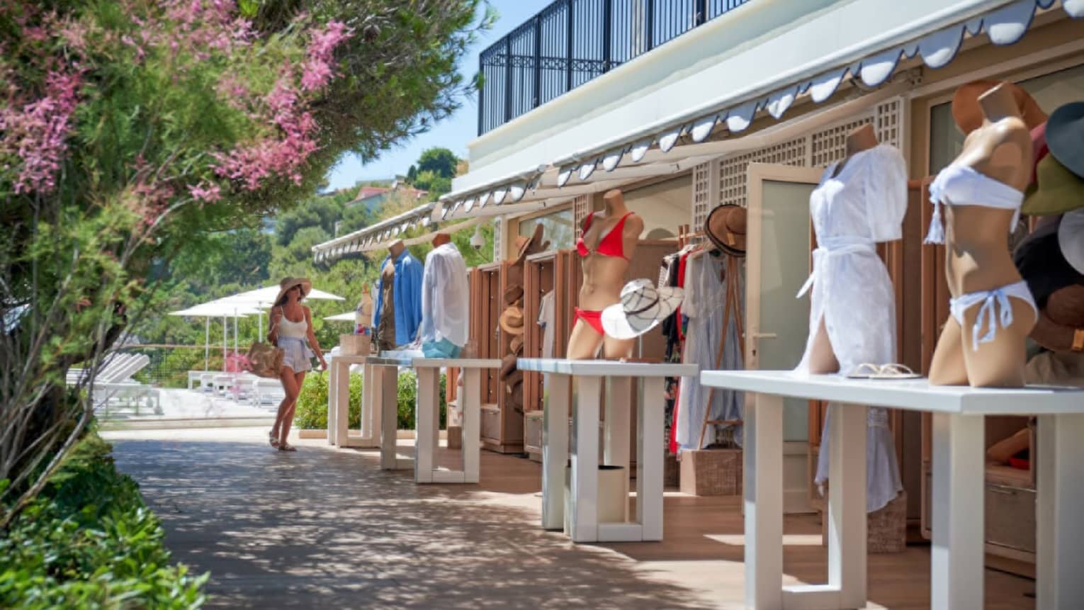 Woman shopping at outdoor boutique with swimwear on tabletop mannequinss