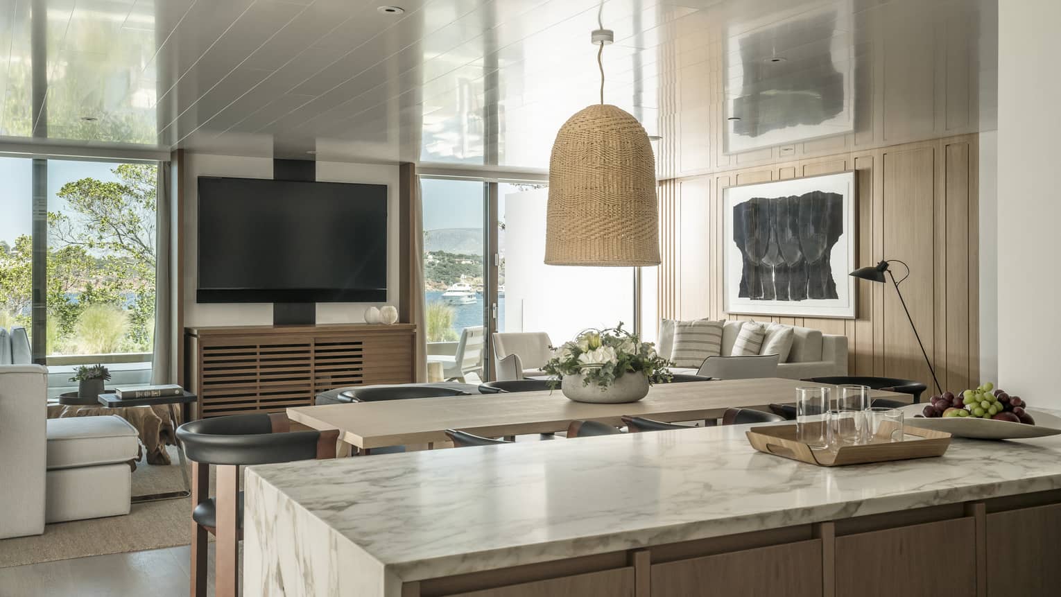 Nafsika One Bedroom Terrace Suite with Pool marbled kitchen counter overlooking dining/living room with rectangular dining table, white sofa, flat screen TV