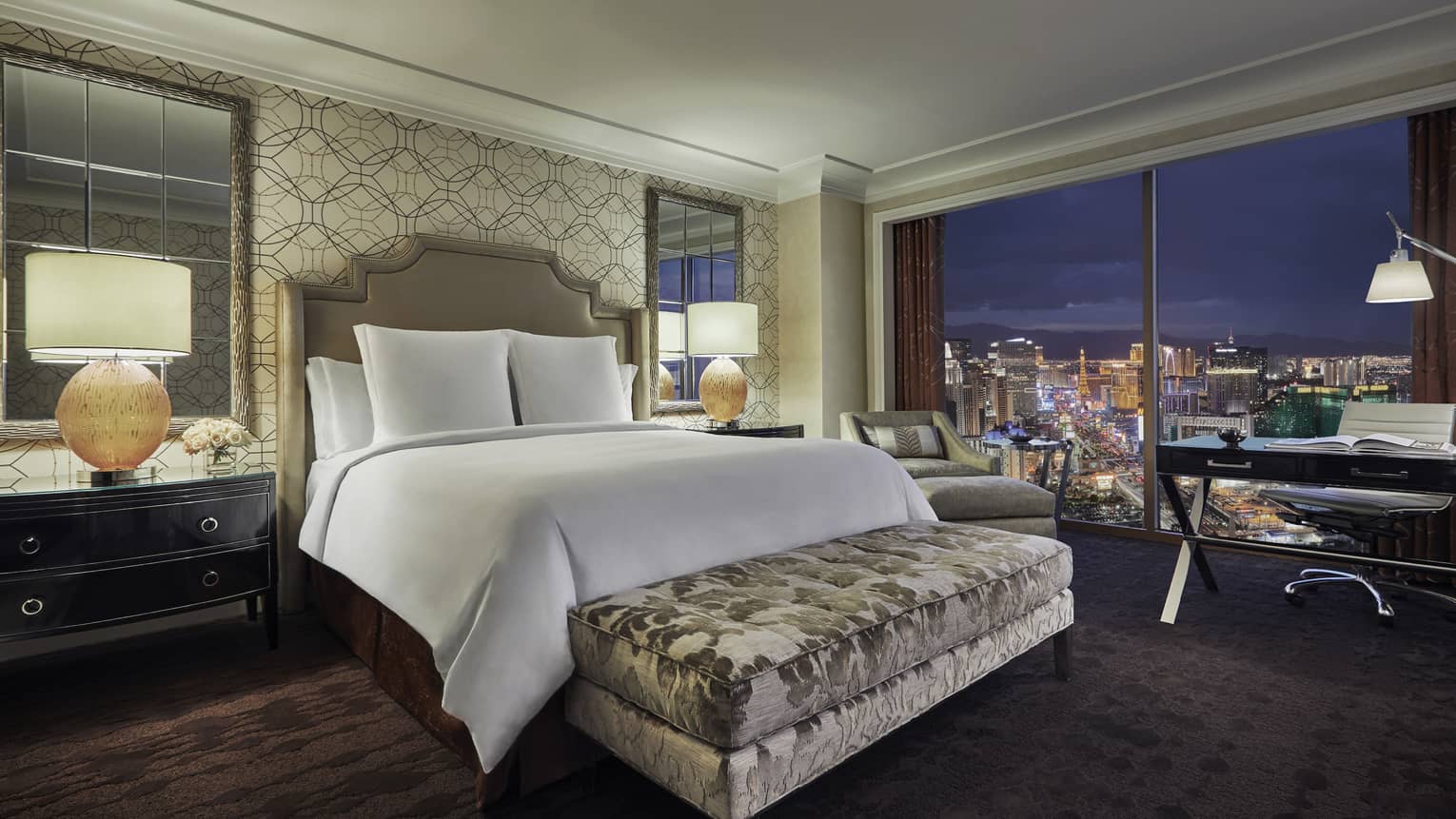 Strip-View Room bed with padded headboard, silver velvet bench, window overlooking Vegas lights at night