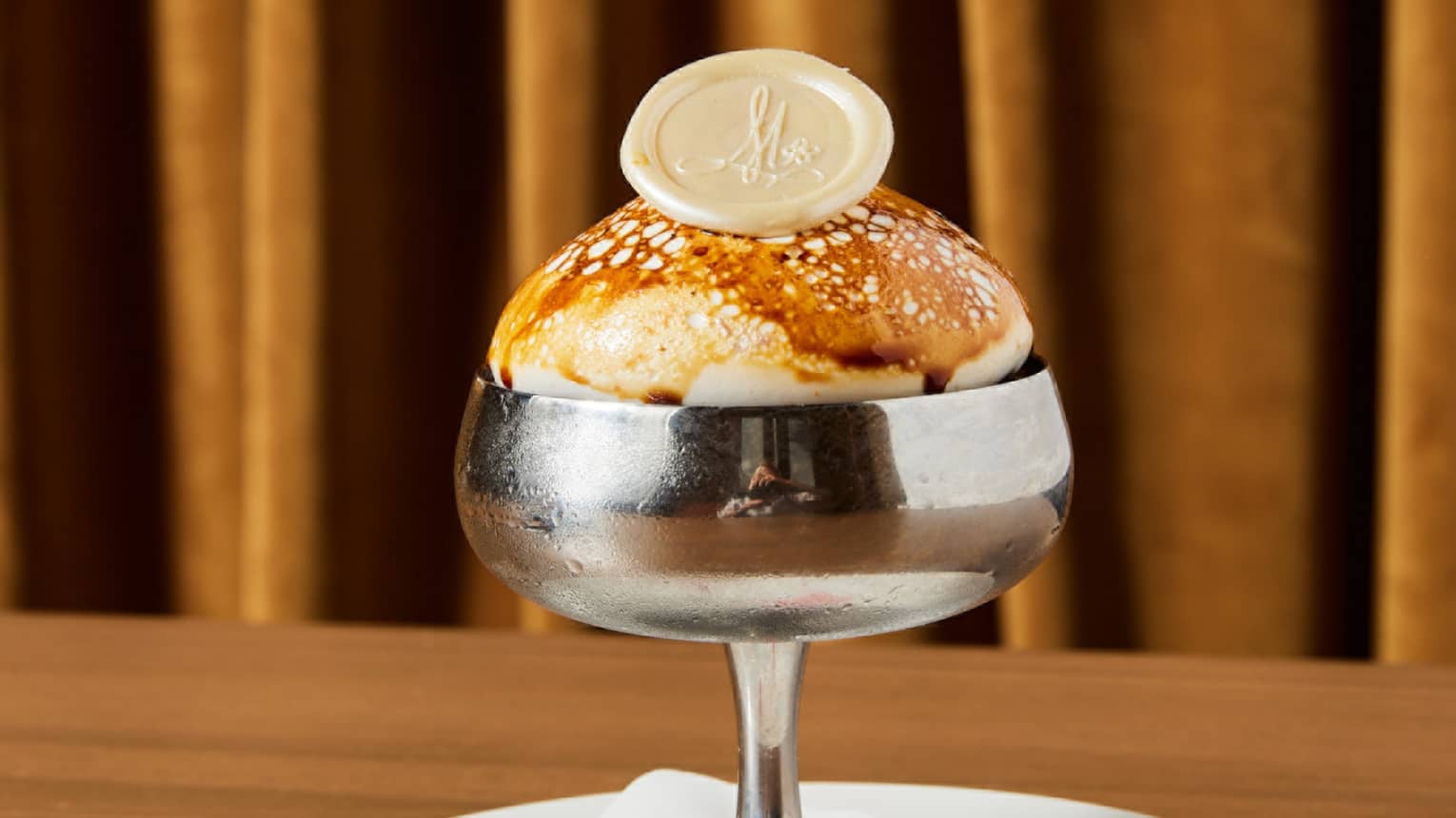 A dessert in a stainless steel glass on a plate
