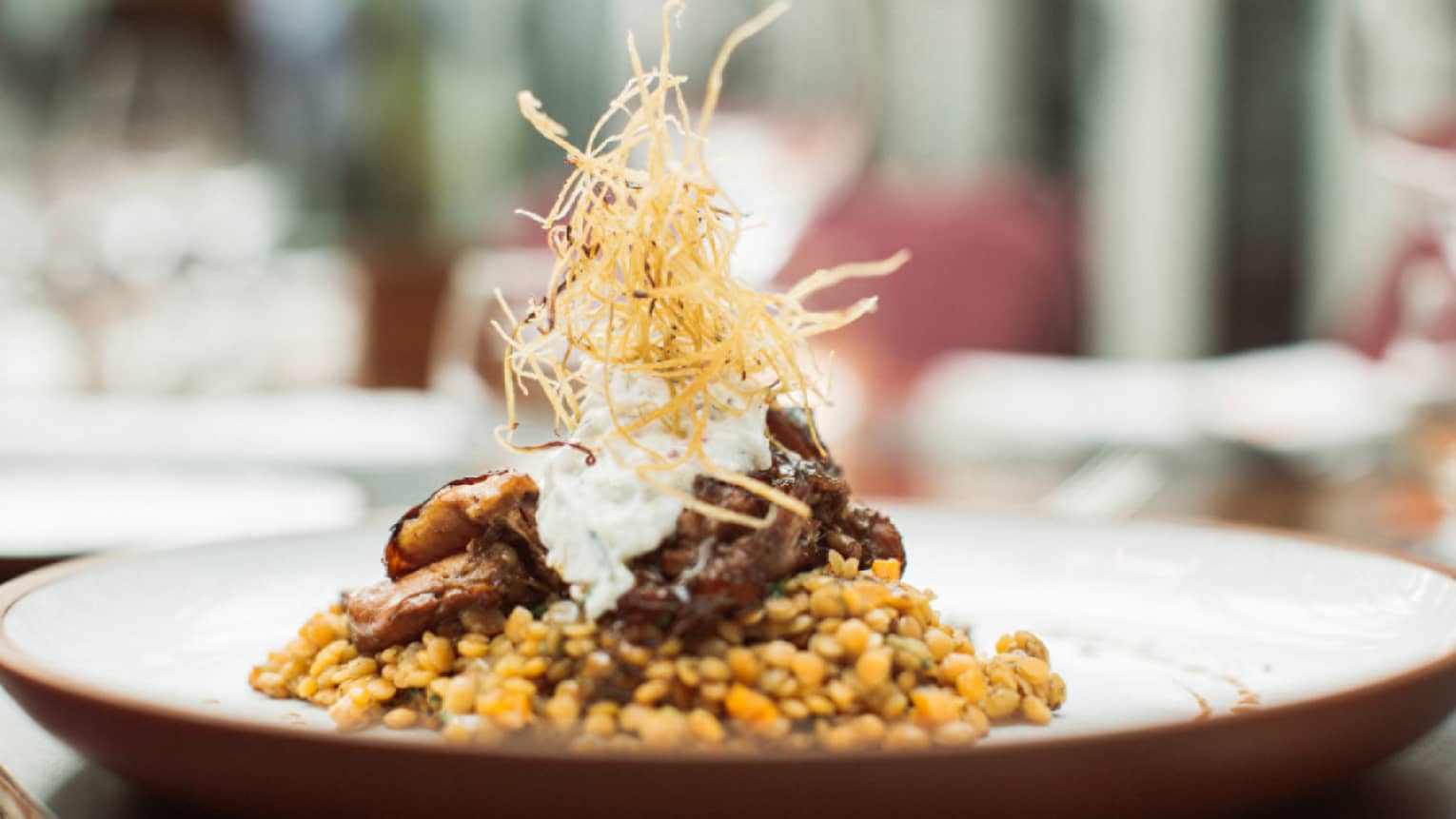 Braided lamb is served on top of Turkish lentils and topped with crispy onion