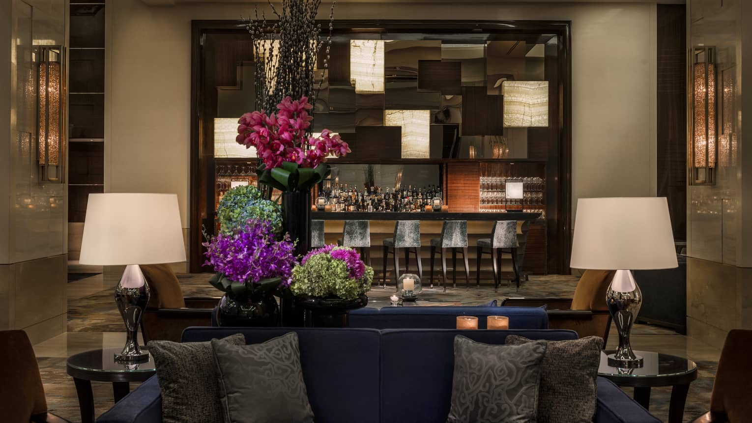 Opus Bar with grey stools behind lounge sofas, purple flowers
