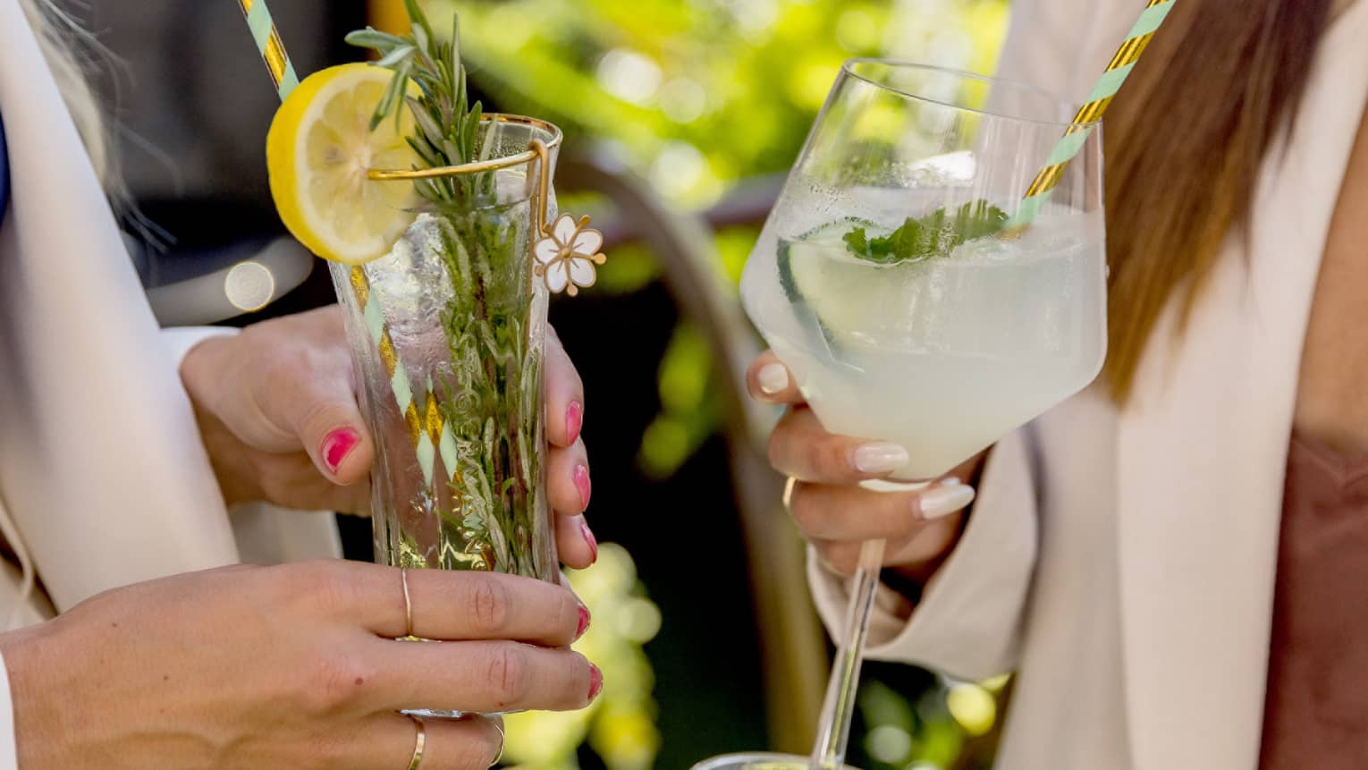 Two women holding cocktails on a sunny day.