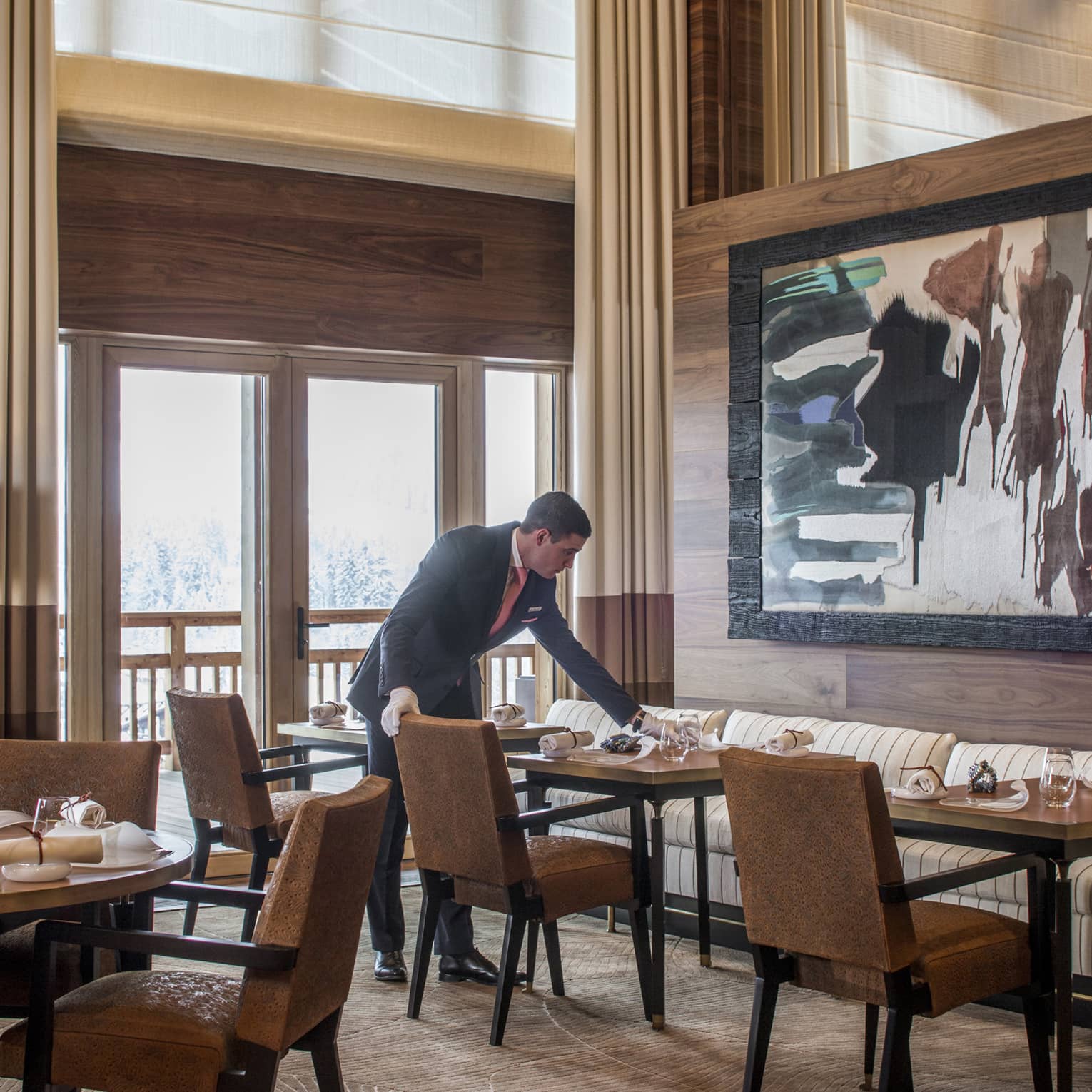 Server sets dining table under large, framed abstract painting in Le 1920 restaurant