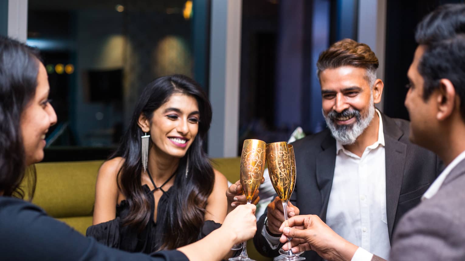 Group of smiling friends toast with gold champagne flutes