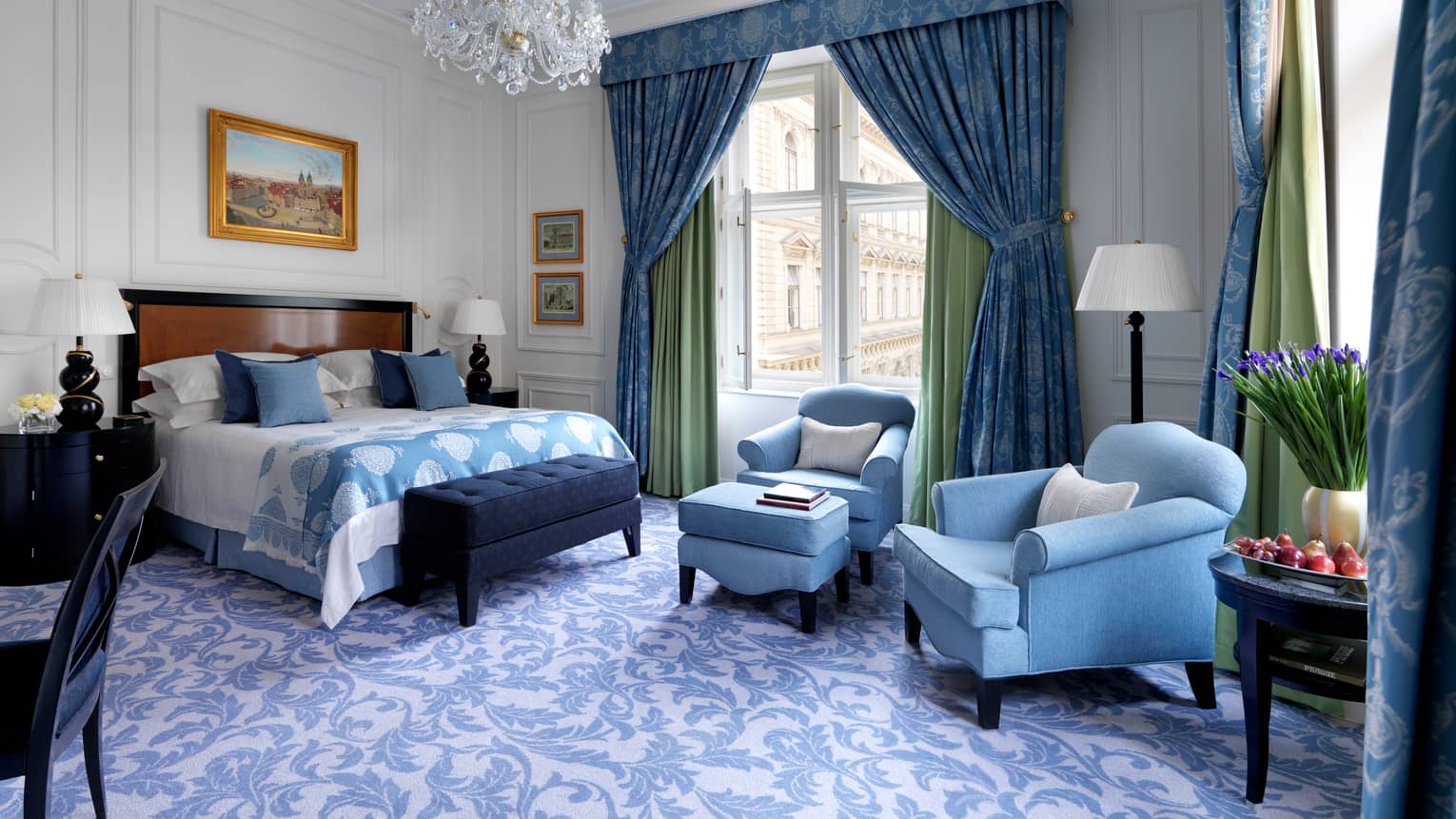 Renaissance Room with powder-blue decor, plush armchairs and footstool beside bed, blue-and-white carpet