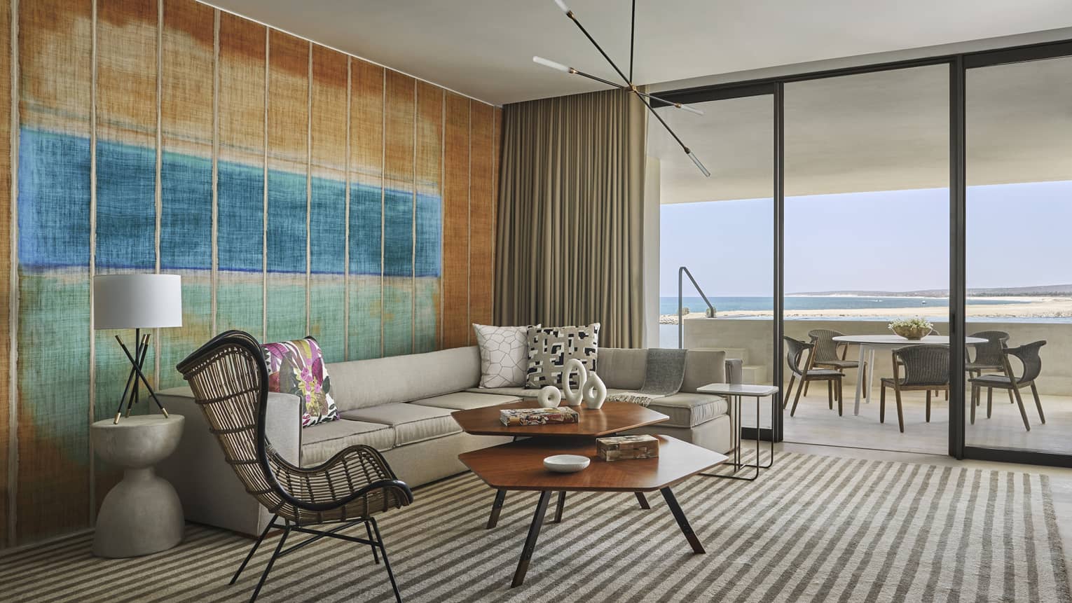 Living room with grey sofa, whicker arm chair, modern wooden coffee table, art wall