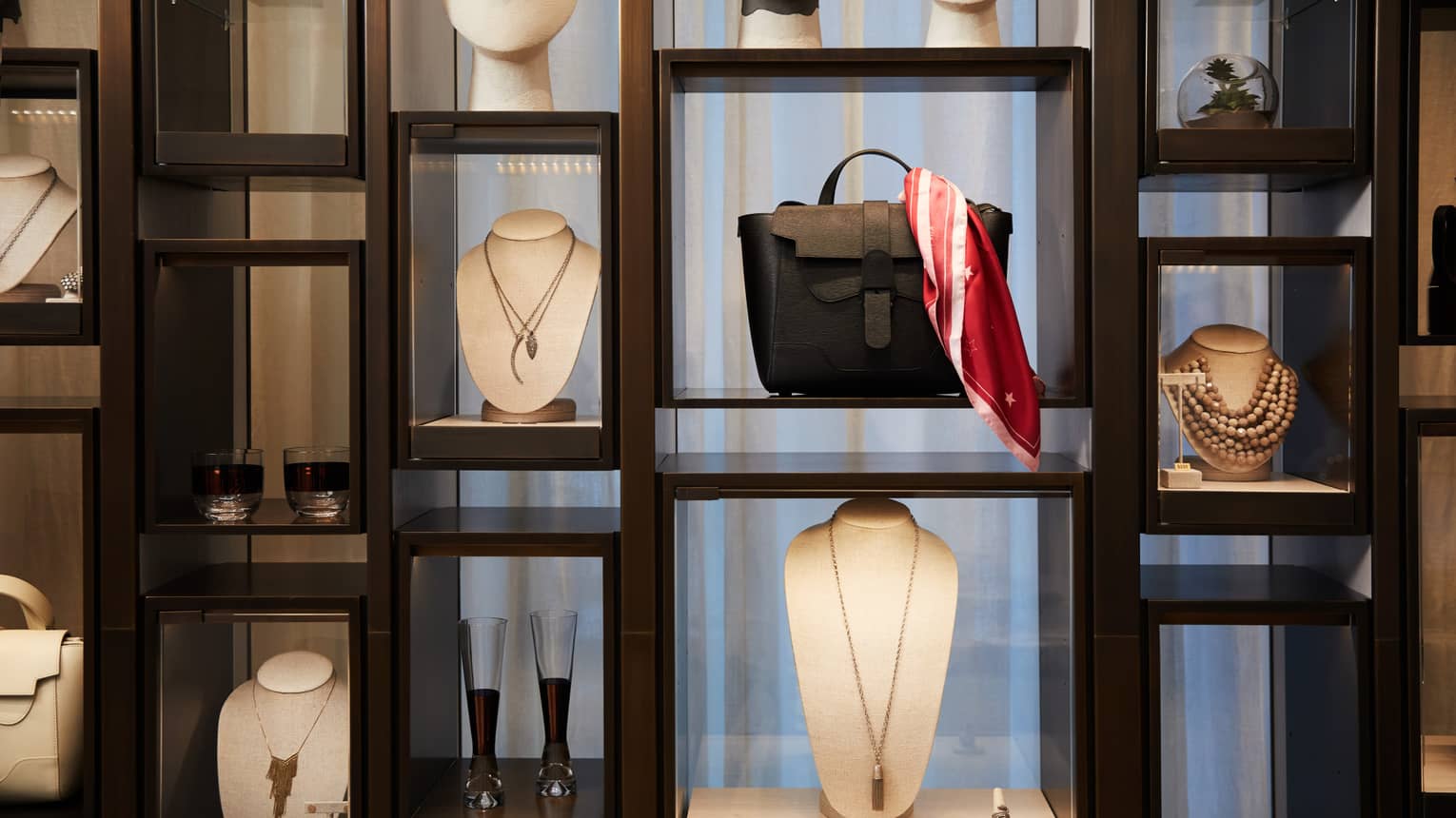 Boutique retail store shelf with designer necklaces, handbag, cocktail glasses 