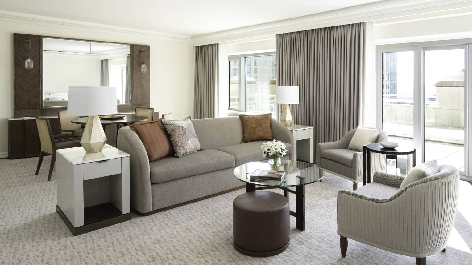 One Bedroom suite living room with grey sofa, chair near bright patio door