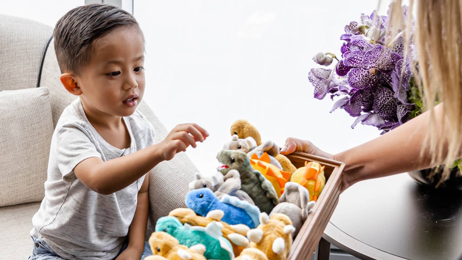 A child being offered a stuffed animal by a hotel team member.