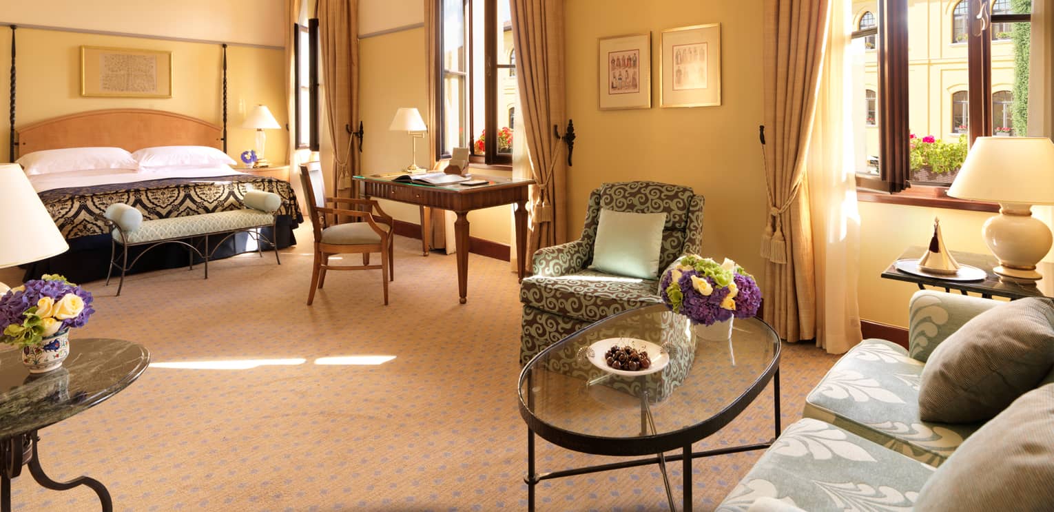 Premier Room seating area, glass coffee table, bed, tall windows