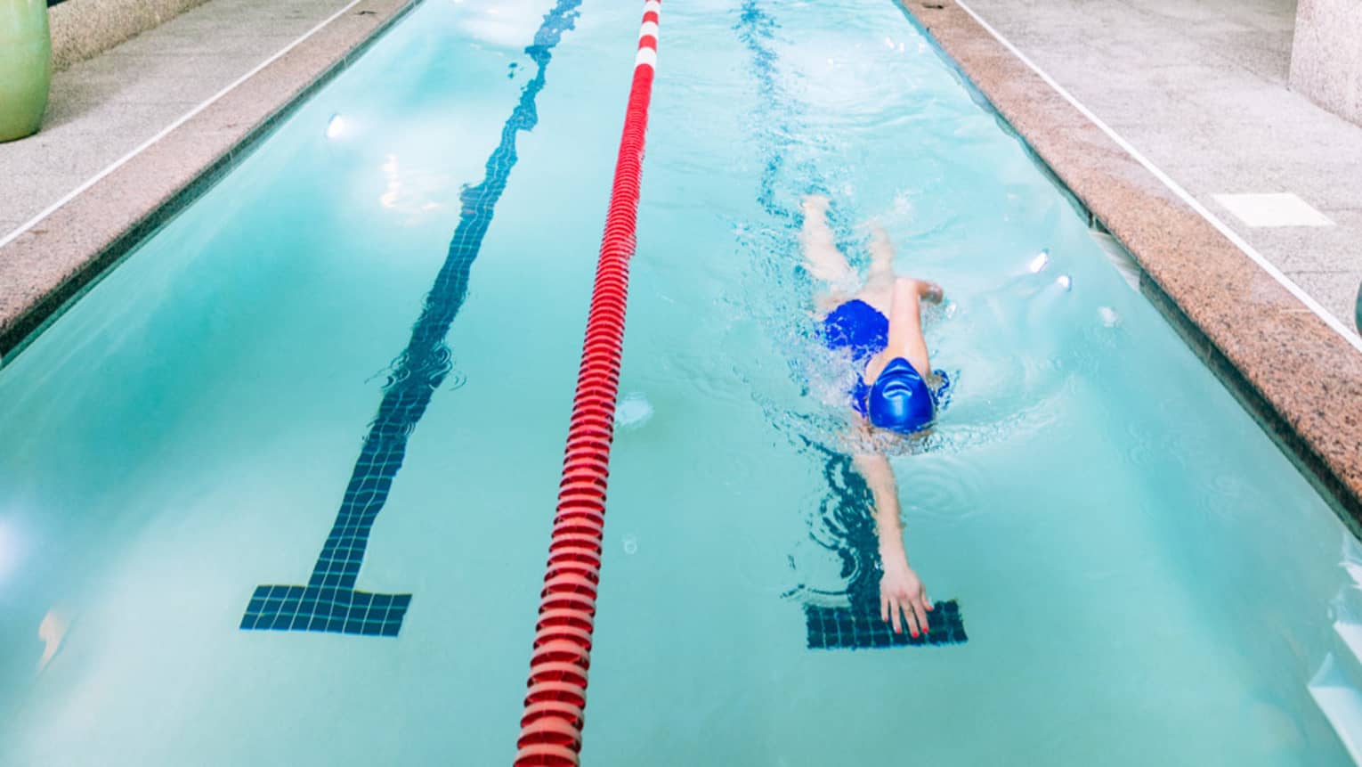 A woman swims laps in an olympic-sized pool