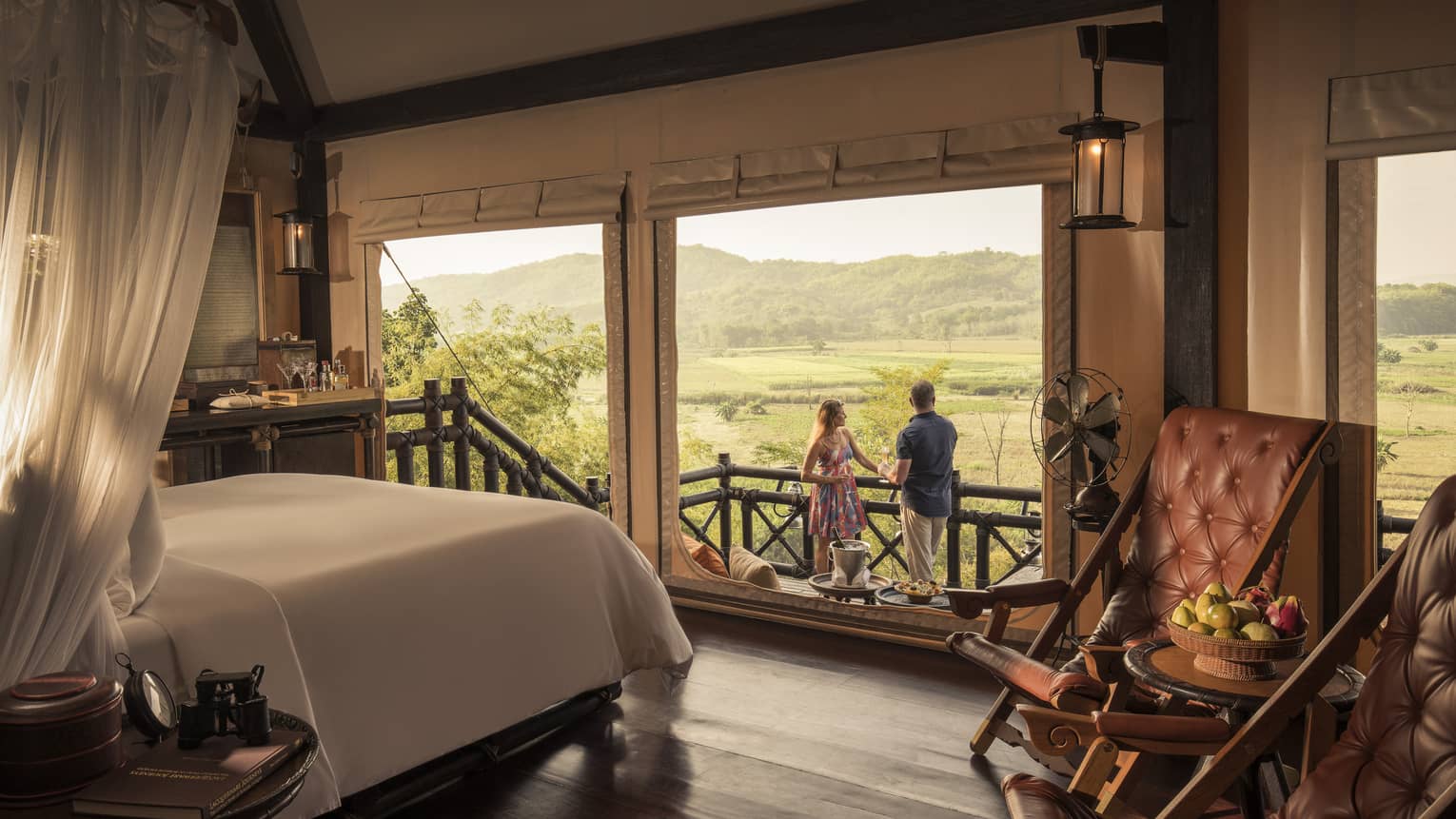 Couple enjoys cocktails at Tent Sundowner, overlooking fields and mountains