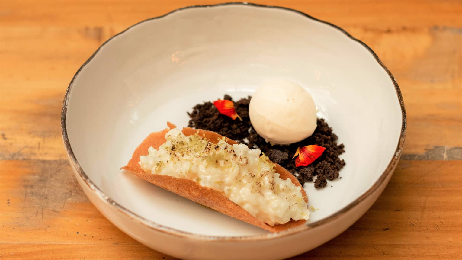 A dessert with ice cream and chocolate in a white bowl.