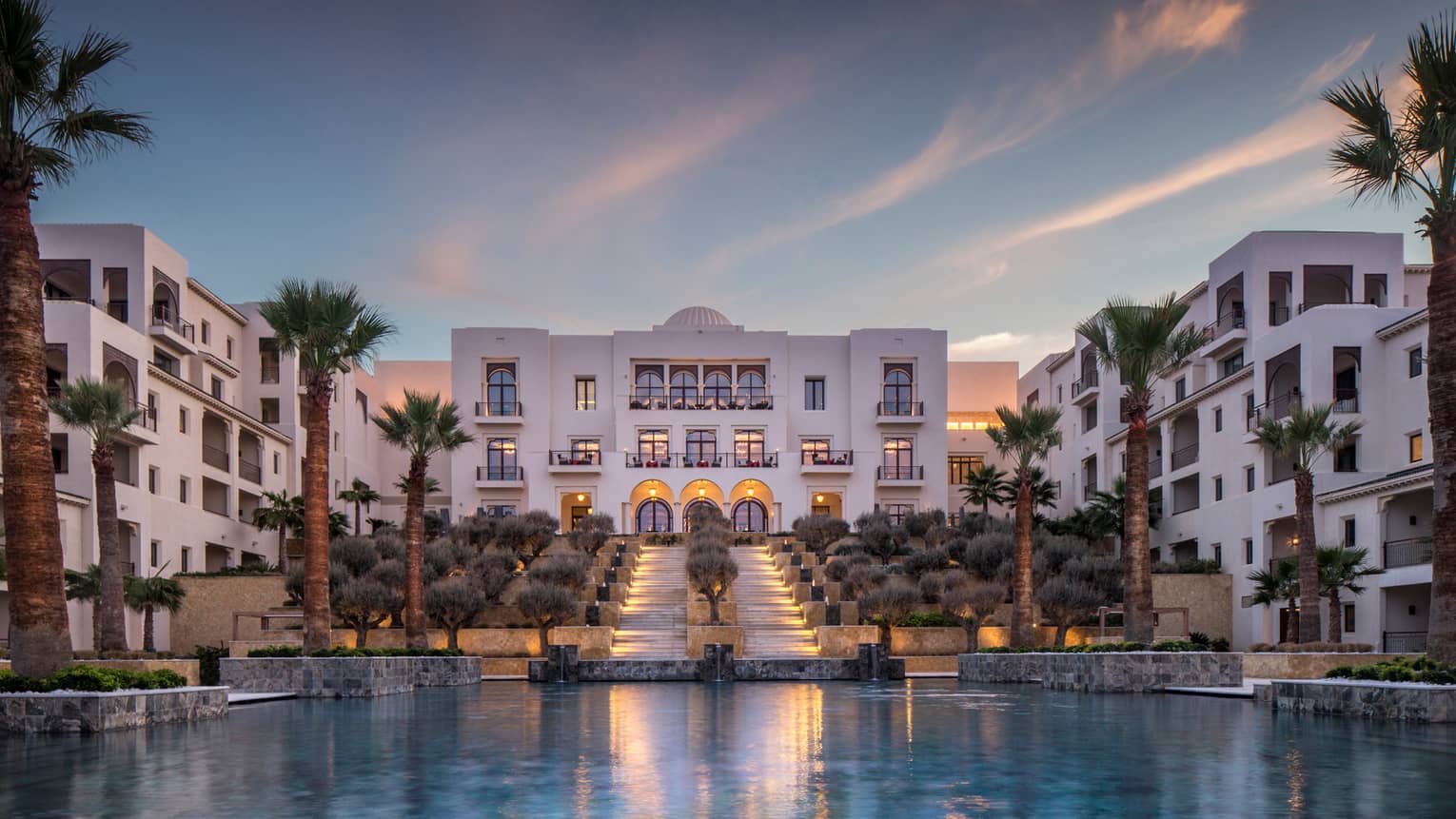 Four Seasons Hotel Tunis modern white buildings around pool, palm trees at sunset