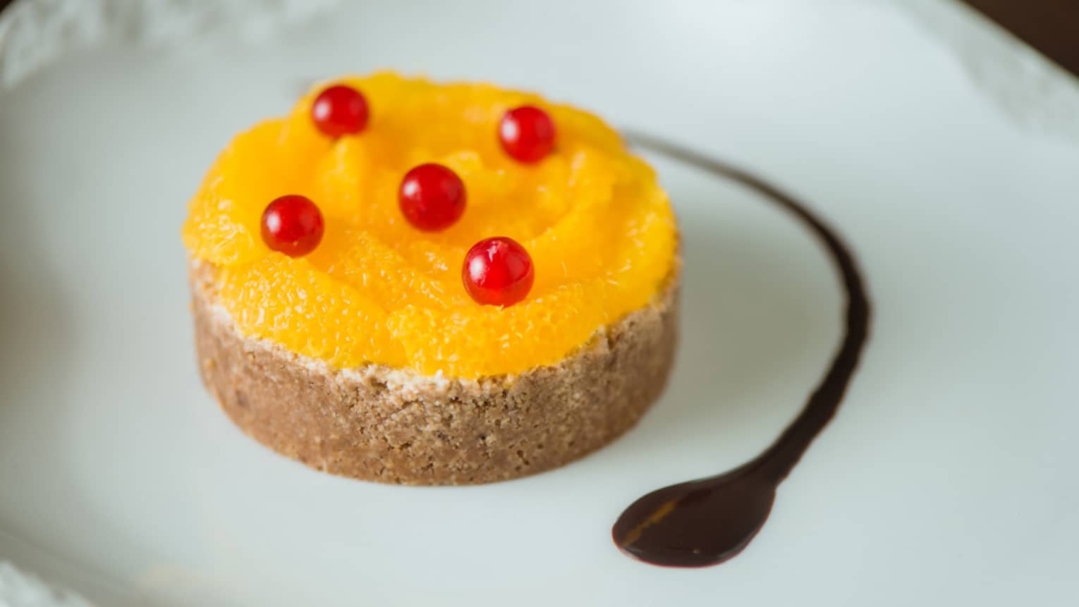 A small orange tart with tiny red berries on top.