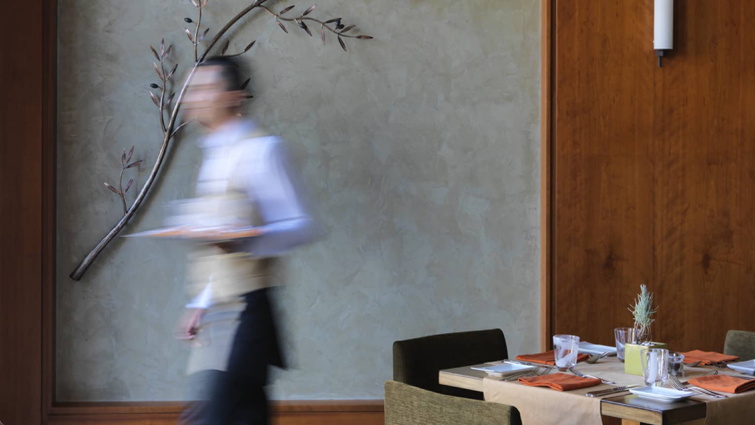 Waiter walking quickly past restaurant dining table