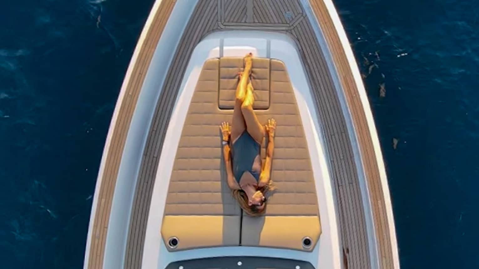 View from above of woman sunbathing on front deck of yacht.