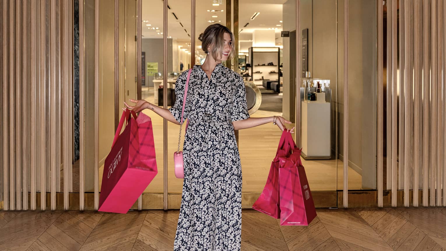 Person with arms full of pink shopping bags leaves Hotel Renfrew Ogilvy department store