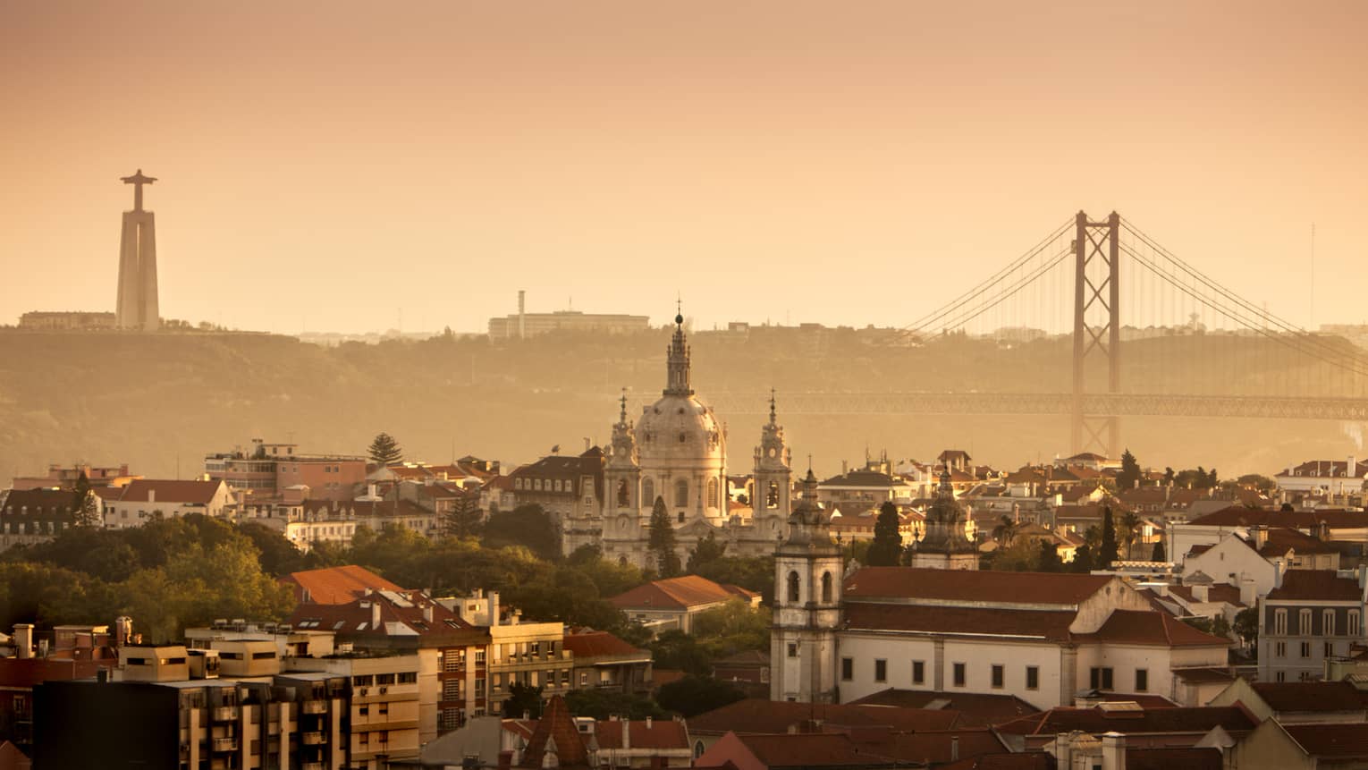 Orange haze over Lisbon buildings, skyline and bridge at sunset