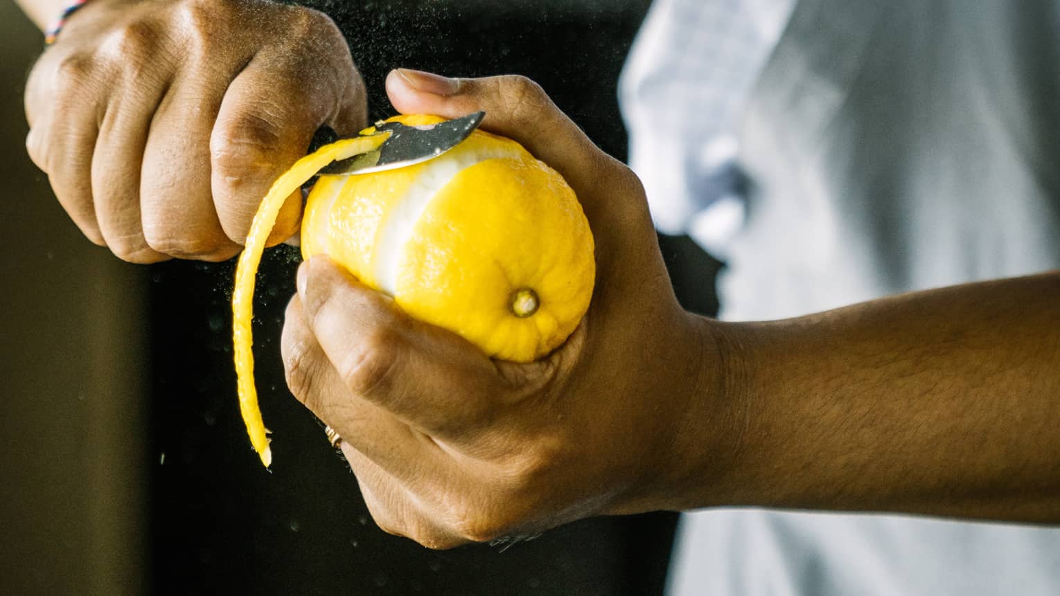 Close up of a bartender peeling a lemon
