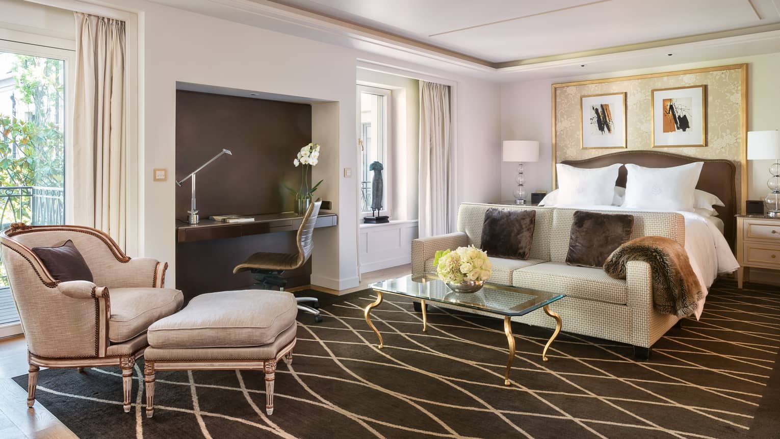 Sunny loft suite with garden view, dark brown area rug, cream furniture, modern desk by bed