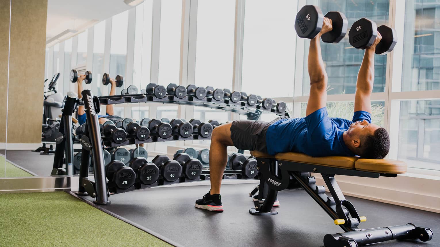 A man lifting two weight while laying on a bench.