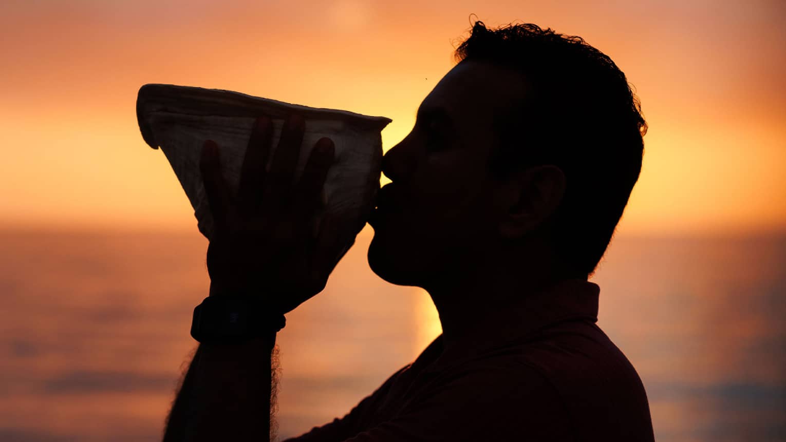 A man sipping a cocktail at sunset on the beach
