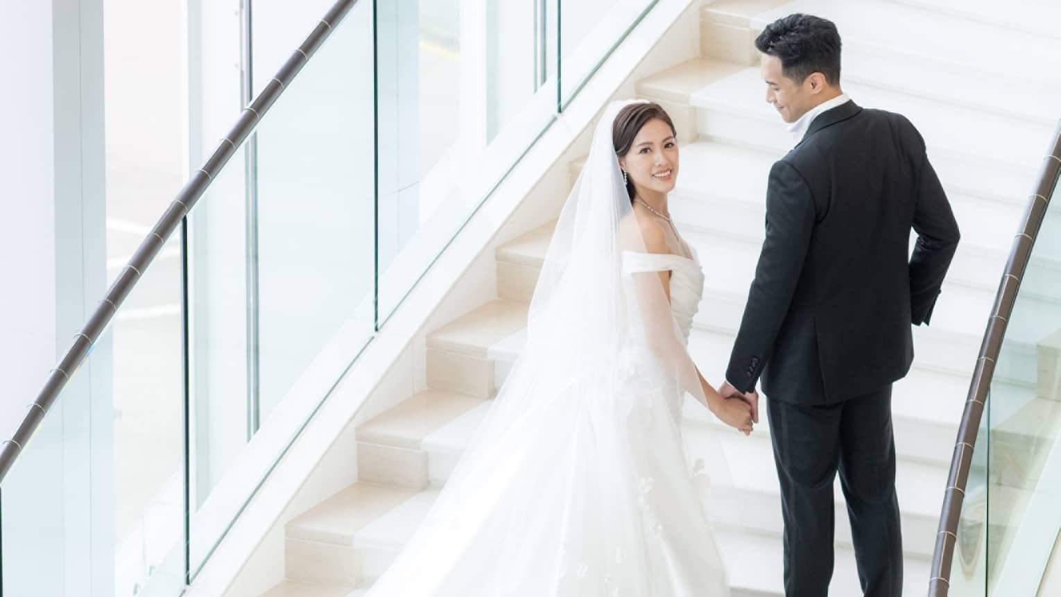 Bride and groom stand on stunning curved staircase at Four Seasons Hotel Hong Kong