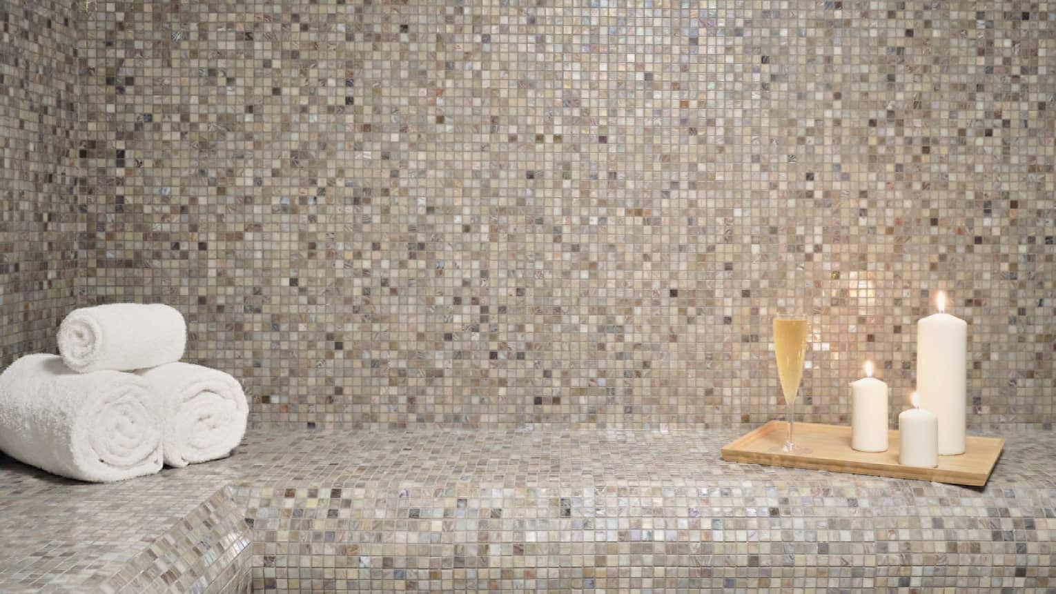 Sauna room with towels, candles and glass of wine.