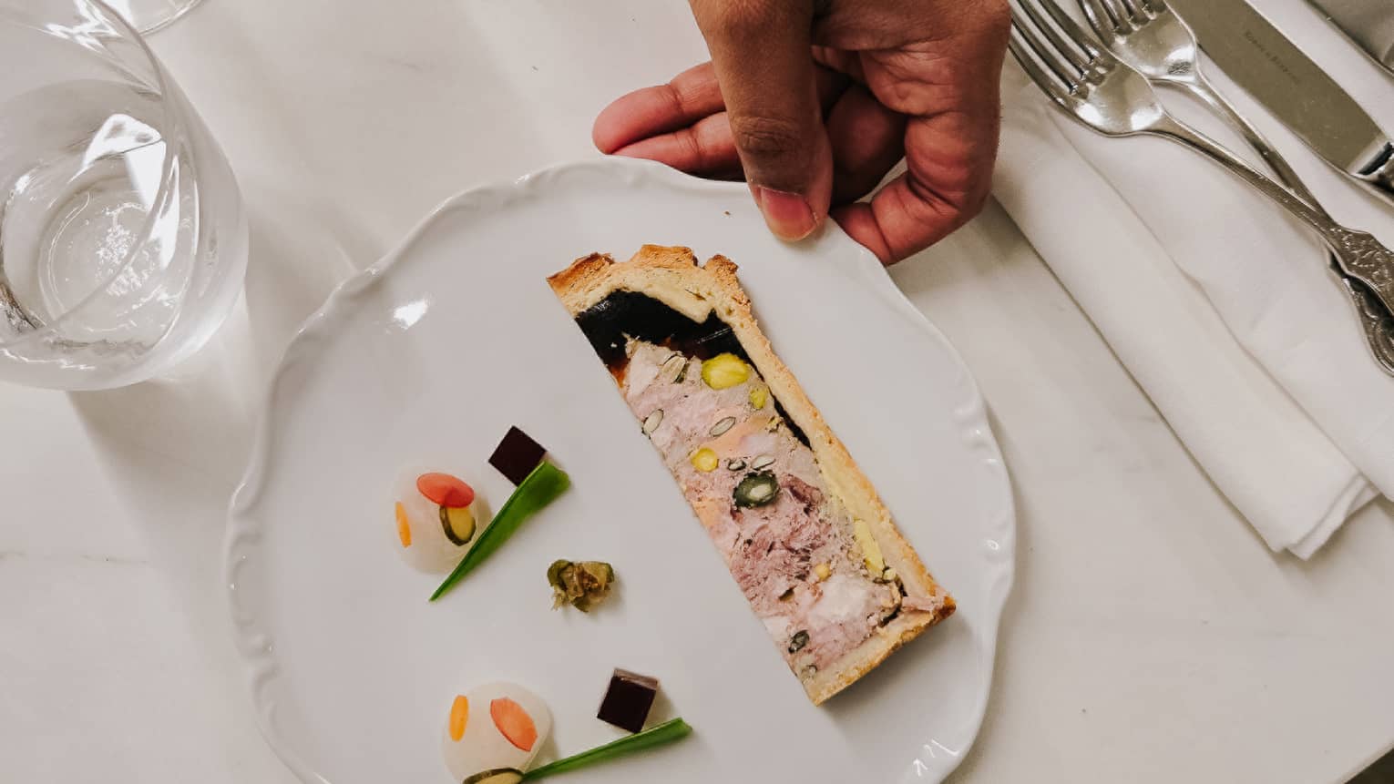 A culinary dish with silverware and wine glasses on the side