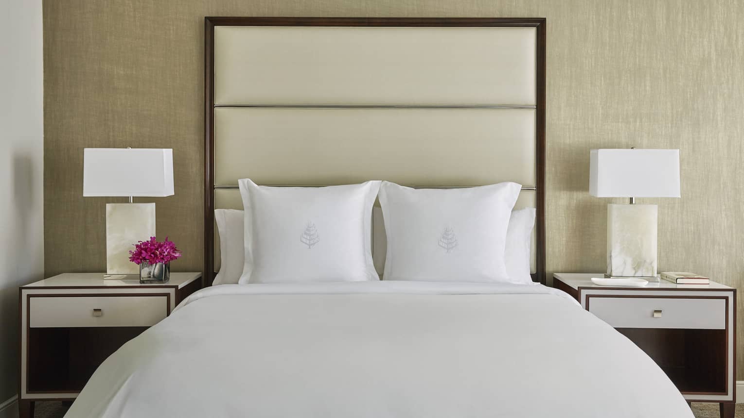 Deluxe Accessible Room head-on view of bed with white linens, tall padded beige headboard, nightstands with lamps