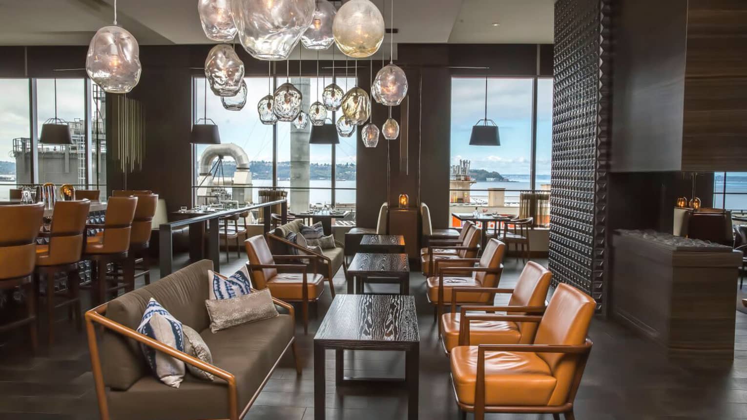 Goldfinch Tavern dining room sofas, leather chairs under hanging glass lights