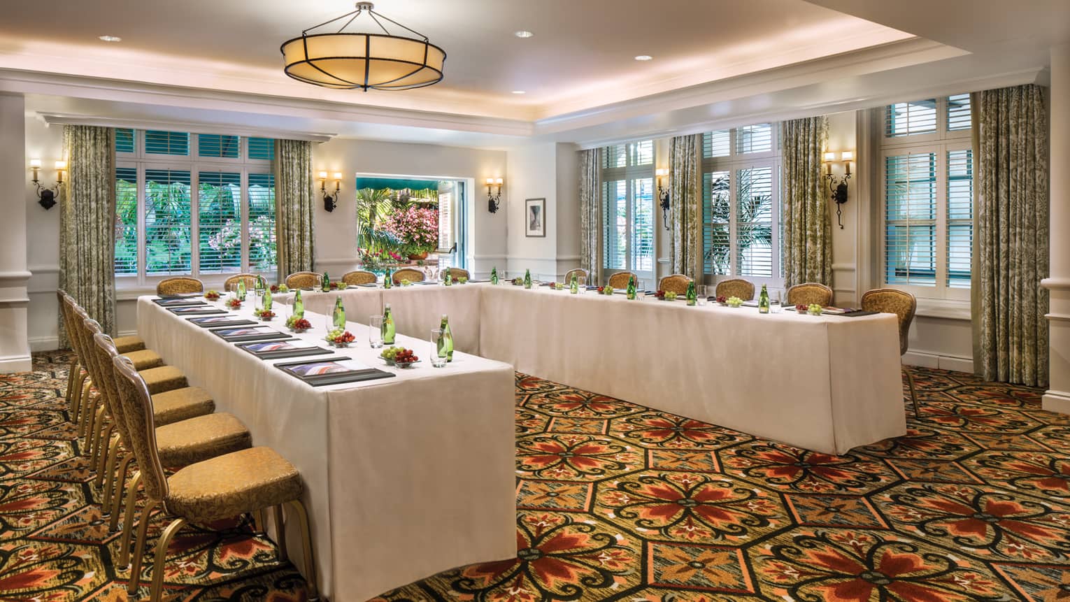 El Jardin carpeted meeting room with modular tables set with water bottles, fresh grapes