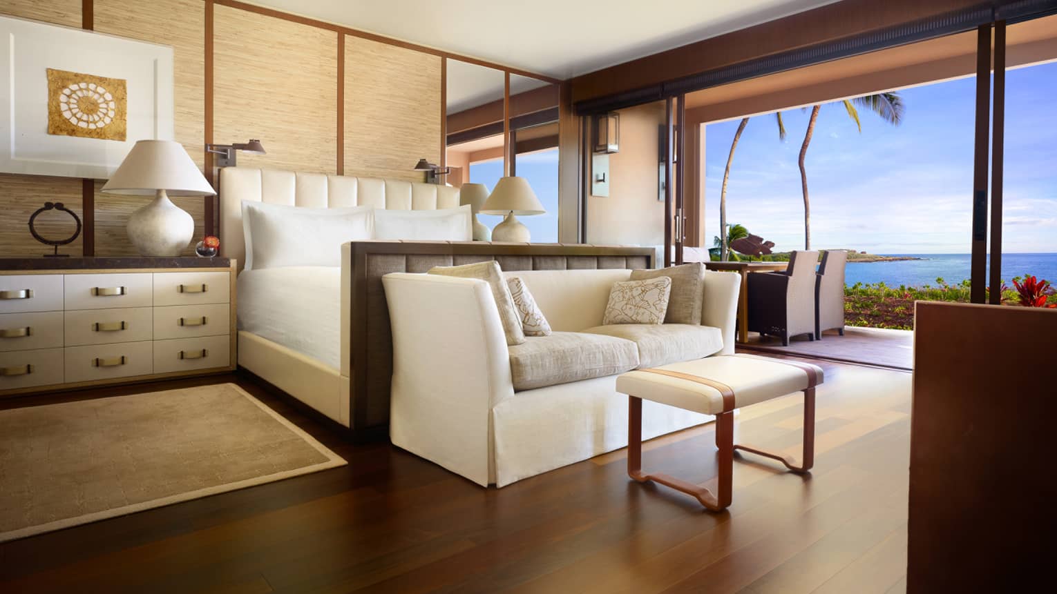 Ohana Prime Oceanfront Suite dresser beside bed, white sofa at foot, open wall to patio, dining table