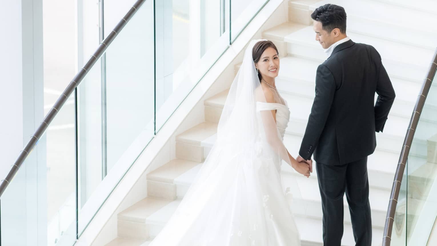 Bride and groom stand on stunning curved staircase at Four Seasons Hotel Hong Kong