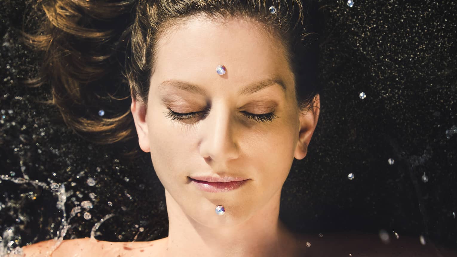 A woman enjoys a facial; two "black diamonds" are placed on forehead and chin